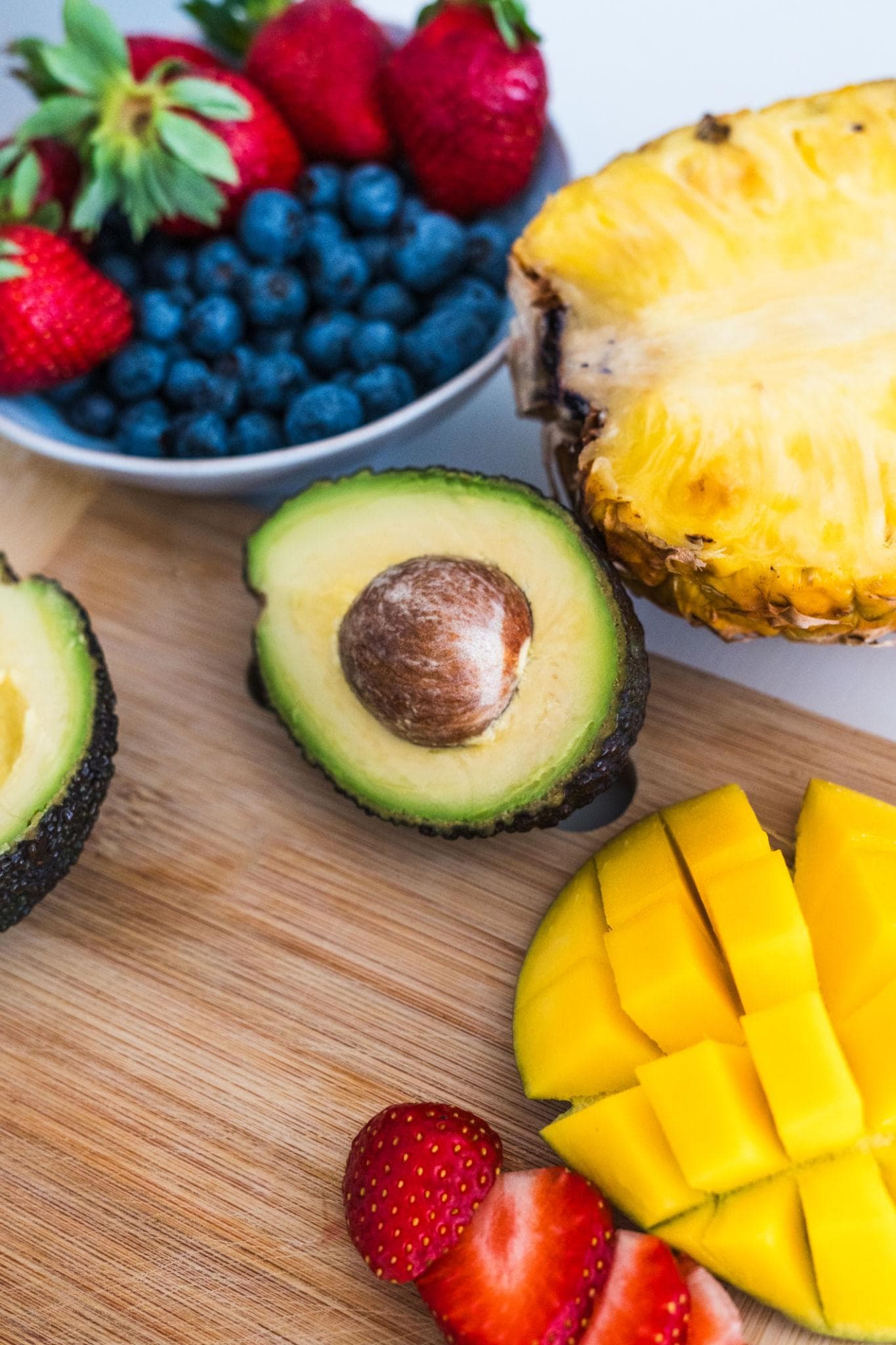 Fresh fruit and avocado on a cutting board in natural light